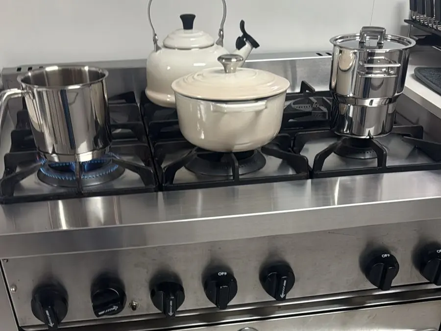 Fogão inox de seis bocas com panelas no fogo
